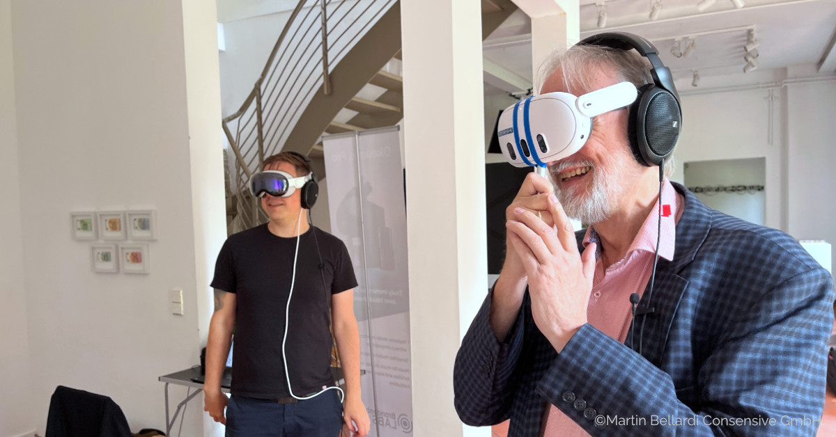 Two men are standing in a room wearing VR headsets.